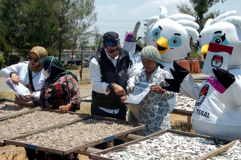 Sejumlah anggota KPU bersama maskot Pemilu 2024 Sulu dan Sura menerangkan partai peserta pemilu kepada buruh jemur ikan asin saat sosialisasi Pemilu 2024 di Tempat Pelelangan Ikan (TPI) Suradadi, Kabupaten Tegal, Jawa Tengah, Senin (11/9/2023). Sosialisasi tersebut untuk memberikan edukasi dan diharapkan dapat meningkatkan partisipasi masyarakat pada pemilu mendatang. ANTARA FOTO/Oky Lukmansyah