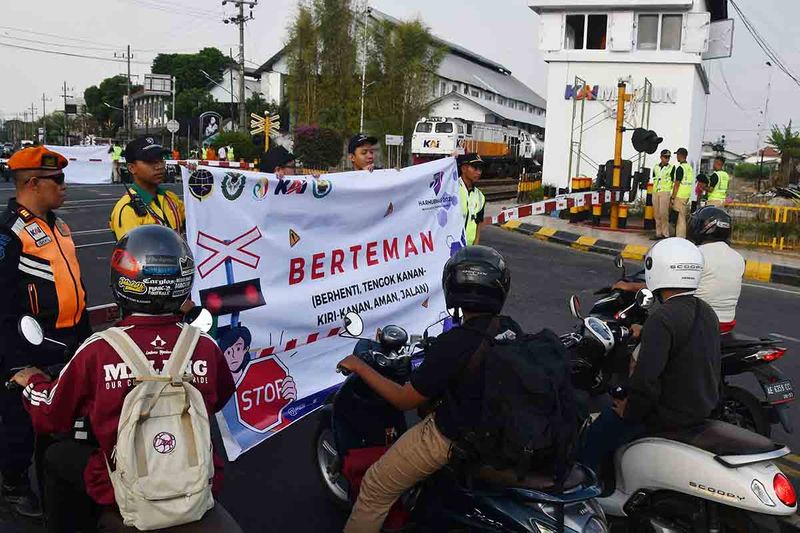 Anggota Komunitas Masyarakat Pecinta Kereta Api bersama Polsuska membentangkan spanduk saat melakukan kampanye keselamatan berlalu lintas di perlintasan sebidang di Kota Madiun, Jawa Timur, Sabtu (16/9/2023). Kegiatan dalam rangka menyambut peringatan Hari Perhubungan Nasional 2023 tersebut untuk meningkatkan kesadaran masyarakat dalam menaati aturan lalu lintas, menyusul masih sering terjadi kecelakaan di perlintasan kereta api. ANTARA FOTO/Siswowidodo