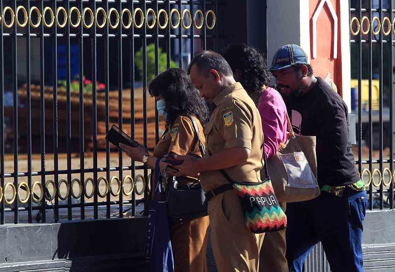 Sejumlah pegawai ASN melakukan absen digital di luar pagar Kantor Gubernur Provinsi Papua yang disegel warga Suku Kayo Pulau di Kota Jayapura, Papua, Senin (18/9/2023). Penyegelan dilakukan untuk meminta ganti rugi atas tanah yang menjadi hak milik ulayat Suku Kayo Pulau. ANTARA FOTO/Gusti Tanati