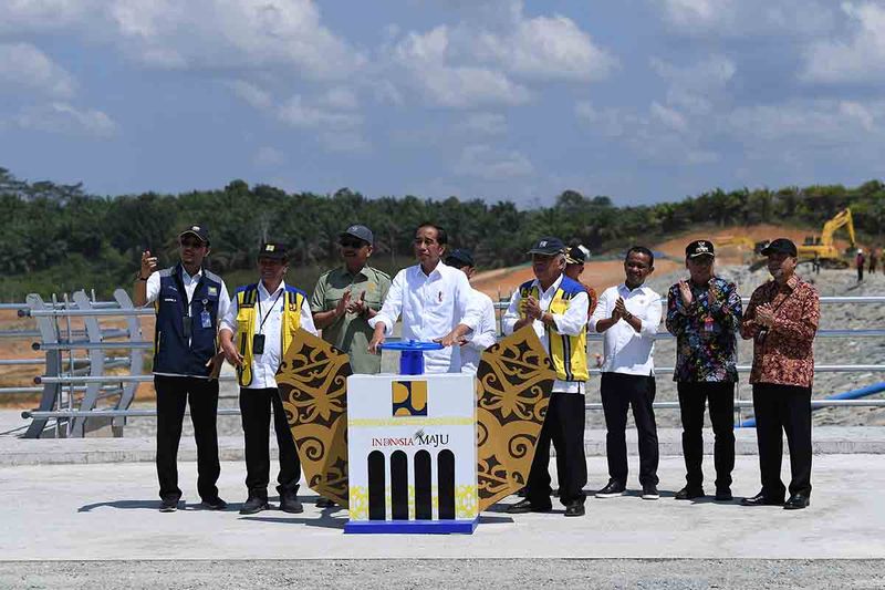 Presiden Joko Widodo (keempat kiri) didampingi Kepala Otorita IKN Bambang Susantono (ketiga kiri), Menteri PUPR Basuki Hadimuljono (keempat kanan), Menteri Investasi/Kepala BPKM Bahlil Lahadalia (ketiga kanan) beserta jajaran memutar tuas untuk membendung air Bendungan Sepaku Semoi di Kabupaten Penajam Paser Utara, Provinsi Kalimantan Timur, Kamis (21/9/2023). Presiden melakukan pengisian awal atau impounding bendungan yang dibangun untuk melayani pemenuhan air baku di kawasan IKN dan sekitarnya. ANTARA FOTO/Sigid Kurniawan