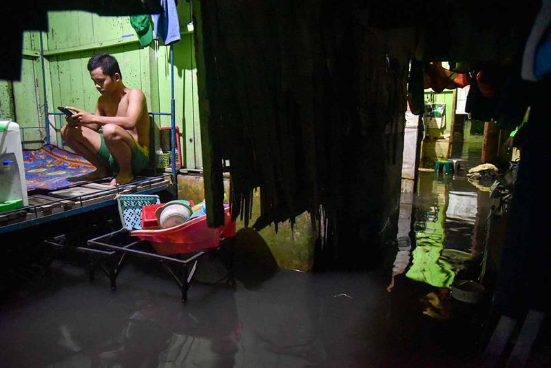 Warga menunggu air surut di dalam rumahnya yang terendam banjir di Medan, Sumatera Utara, Senin (25/9/2023). Banjir tersebut akibat curah hujan yang tinggi dan buruknya sistem drainase di daerah tersebut. ANTARA FOTO/Fransisco Carolio