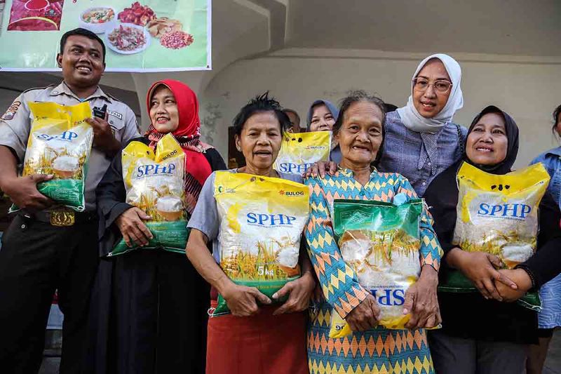 Warga membawa beras yang dibagikan oleh Menteri Perdagangan Zulkifli Hasan saat kunjungan kerja di pasar tradisional Johar, Semarang, Jawa Tengah, Selasa (26/9/2023). Kunjungan tersebut dalam rangka memantau secara langsung harga dan ketersediaan bahan pokok di pasar tradisional dan mendapati harga beras premium 5 kilogram mengalami kenaikan mencapai Rp70 ribu. ANTARA FOTO/Makna Zaezar