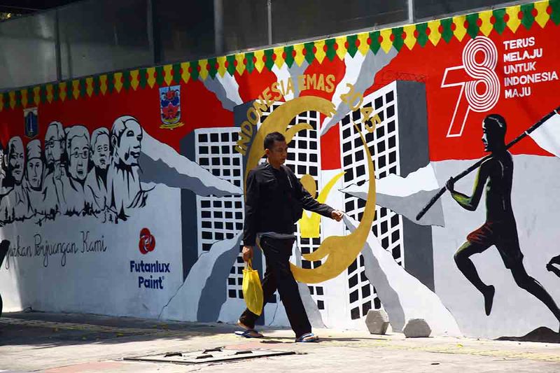 Warga berjalan di depan mural bertema Pemilu 2024 di Jalan Perjuangan Raya, Jakarta, Kamis (28/9/2023). Pemilu serentak Pilpres, Pileg dan Pilkada akan dilakukan 14 Februari 2024. ANTARA FOTO/Reno Esnir