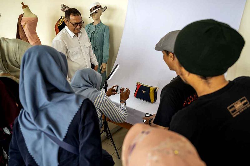 Ketua Aprindo Sumatra Barat Rinaldi (kiri) menyaksikan seorang pedagang pasar praktik memotret saat pelatihan fotografi memotret produk menggunakan smartphone untuk pedagang Pasa Ateh di Bukittinggi, Sumatra Barat, Jumat (29/9/2023). Pelatihan fotografi rangkaian dari Pameran Fotografi Selayang Minang tersebut digelar GFJA bersama ANTARA Sumbar berkolaborasi dengan Pemerintah Kota Bukittinggi dan Aprindo. ANTARA FOTO/Dok. GFJA/Firman Aditya Warman