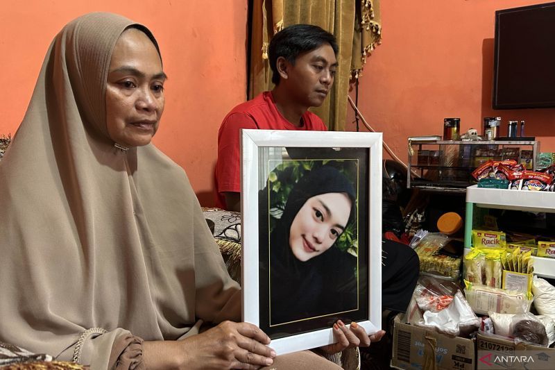 Siti Mardiyah (kiri) didampingi anak pertamanya Andik Kurniawan, memegang foto Mitha Maulidia yang meninggal dunia dalam peristiwa Tragedi Kanjuruhan, di kediamannya di Kota Malang, Jawa Timur. ANTARA/Vicki Febrianto.