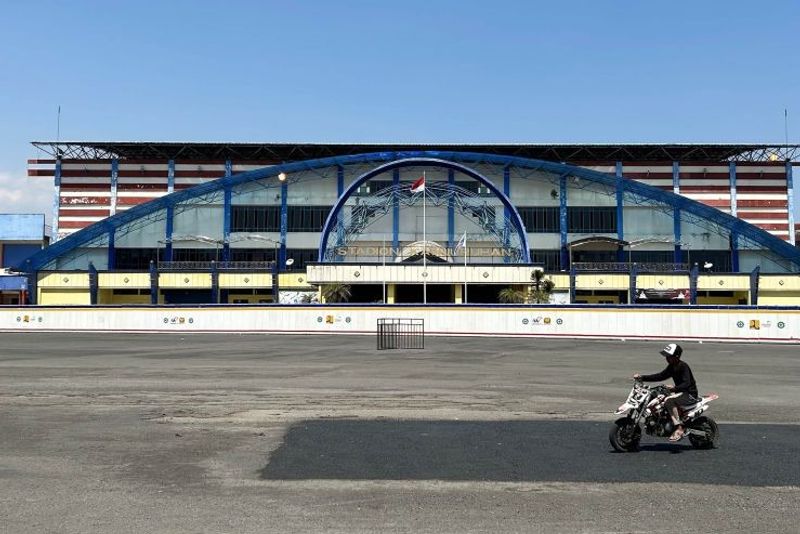 Seorang anak mengendarai sepeda motor mini melintas di depan Stadion Kanjuruhan di Kecamatan Kepanjen, Kabupaten Malang, Jawa Timur yang ditutup pembatas untuk proses renovasi pascatragedi 1 Oktober 2022, Minggu (1/10/2023). ANTARA/Vicki Febrianto.