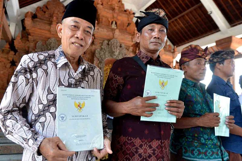 Pengurus tempat ibadah menunjukkan sertifikat tanah yang diterima saat kegiatan penyerahan Sertifikat Hak Atas Tanah Tempat Peribadatan di Denpasar, Bali, Minggu (1/10/2023). Penyerahan sejumlah sertifikat tanah untuk pura dan tanah wakaf untuk masjid yang terdaftar melalui program Pendaftaran Tanah Sistematis Lengkap (PTSL) di wilayah Denpasar dan Gianyar itu dilakukan sebagai upaya untuk memberikan kepastian hukum atas tanah untuk tempat ibadah. ANTARA FOTO/Fikri Yusuf