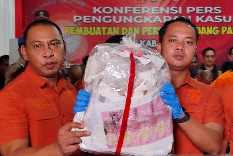 Petugas Kepolisian menunjukkan barang bukti uang palsu Petugas Kepolisian menunjukkan barang bukti uang palsu yang hendak diedarkan para pelaku saat merilis kasus tersebut di Mapolres Gowa, Sulawesi Selatan, Kamis (19/12/2024). ANTARA/Darwin Fatir.
